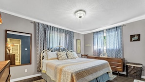 A bedroom with a bed, a dresser, a mirror, and a ceiling light.
