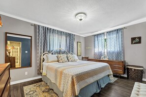 Une chambre à coucher avec un lit, une commode, un miroir et un luminaire au plafond.
