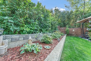 A garden with a stone wall, a bird bath, and various plants.