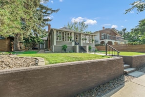 A two-story house with a front porch, a staircase, and a large tree in the yard.