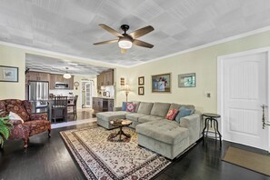 A spacious living room with a sofa, armchair, and a dining area with a table and chairs.