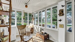 A sunroom with large windows, wicker furniture, and decorative items.