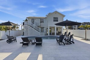 A two-story house with a pool, outdoor seating, and a staircase leading to the upper floor. - Sandy Smiles - Gulf View 1-Min-Beach - Heated Pool (Fort Myers Beach)