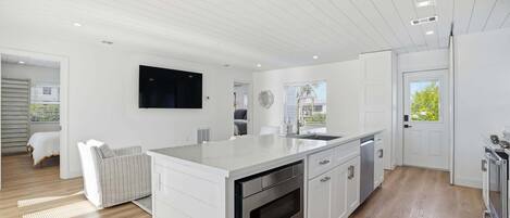 A modern kitchen with white cabinetry, a built-in oven, and a large island with a sink.