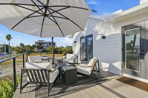 Eine Terrasse mit Gartenmöbeln, einer Feuerstelle und einem großen Sonnenschirm.
