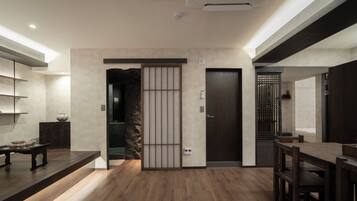 Un intérieur moderne avec un plancher en bois, une porte sombre et une étagère ornée d’objets décoratifs.