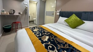 Ein Hotelzimmer mit einem Bett, einem Nachttisch, einem roten Sessel, einem Spiegel und einer Badezimmertür.