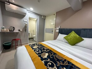 Una camera d'albergo con un letto, un comodino, una sedia rossa, uno specchio e l'accesso al bagno.