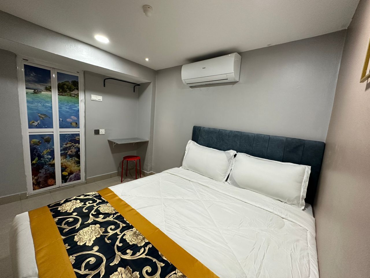 Habitación de hotel con cama, unidad de aire acondicionado, ventana con vista al mar y una mesita.
