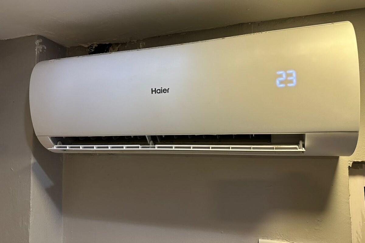 Condizionatore d'aria bianco fissato al muro, con il marchio "Haier" e display digitale che indica la temperatura "23".