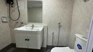 Un baño con lavamanos, espejo y retrete blancos.
