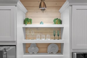 A kitchen with white cabinetry, a wooden countertop, and a shelf with glassware and decorative items. - Hot Tub~1/2 Mi to Beach~Outdoor Fireplace~Dogs OK (Santa Rosa Beach)