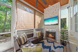 A cozy seating area with a fireplace, a view of the outdoors, and a ceiling fan. - Hot Tub~1/2 Mi to Beach~Outdoor Fireplace~Dogs OK (Santa Rosa Beach)