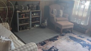A cozy room with a checkered sofa, a wooden cabinet with decorative items, a chair, and a patterned rug.