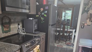 A kitchen with a microwave, stove, refrigerator, and a rug.