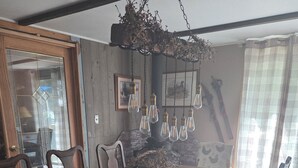 A dining area with a long wooden table, chairs, a woven centerpiece, and hanging light fixtures.