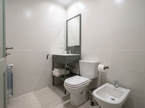 A modern bathroom with a toilet, bidet, and a mirror.