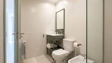 Une salle de bain moderne équipée de toilettes, d’un bidet et d’une douche à parois de verre.