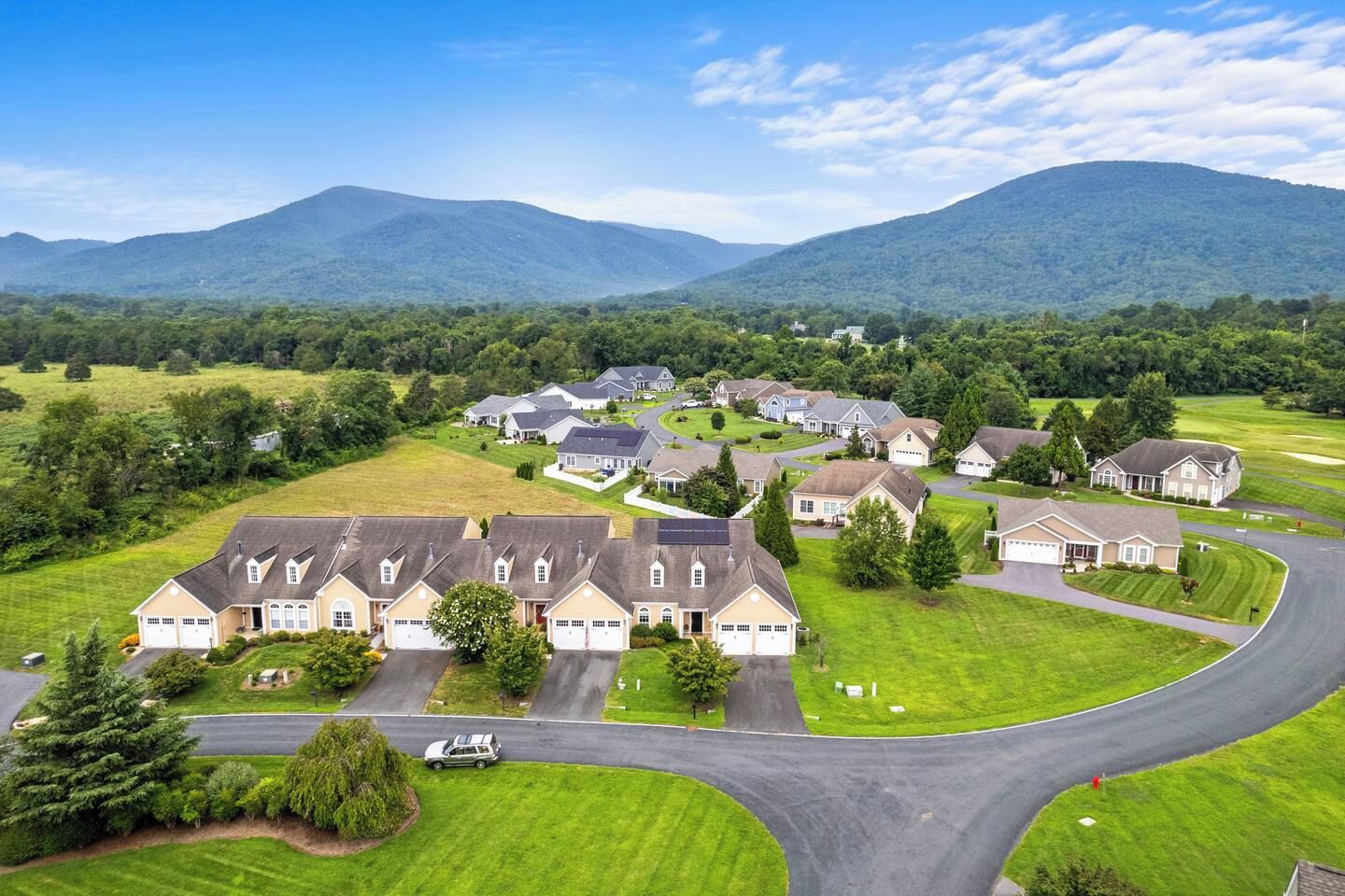 Zona residencial con casas, una carretera curva y montañas al fondo.
