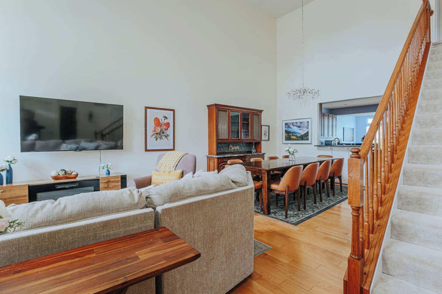 A living room with a sofa, a wooden coffee table, a TV, and a dining area with chairs and a table.