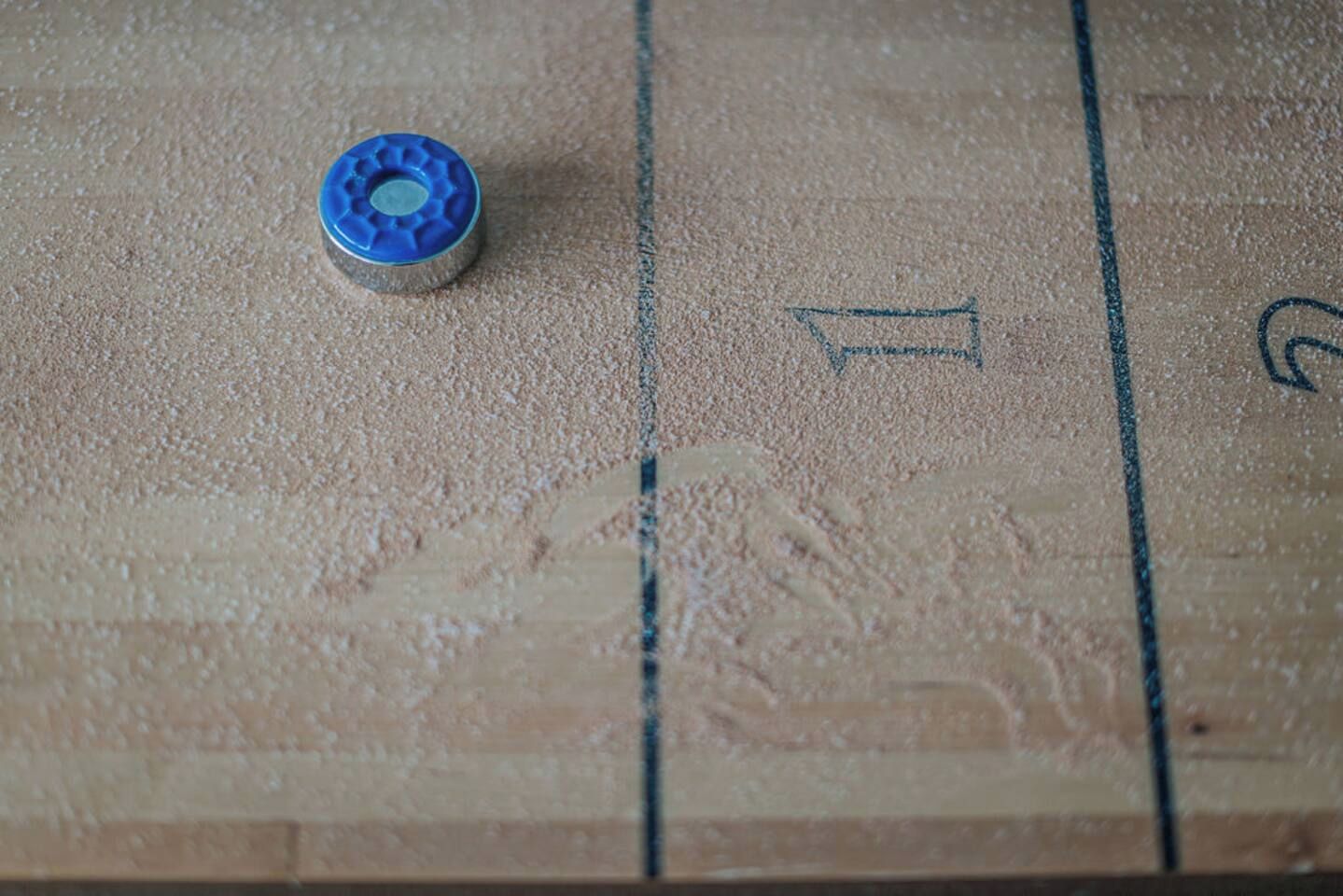 Detailaufnahme einer Holzplatte mit einem blauen Gegenstand und Zahlen.