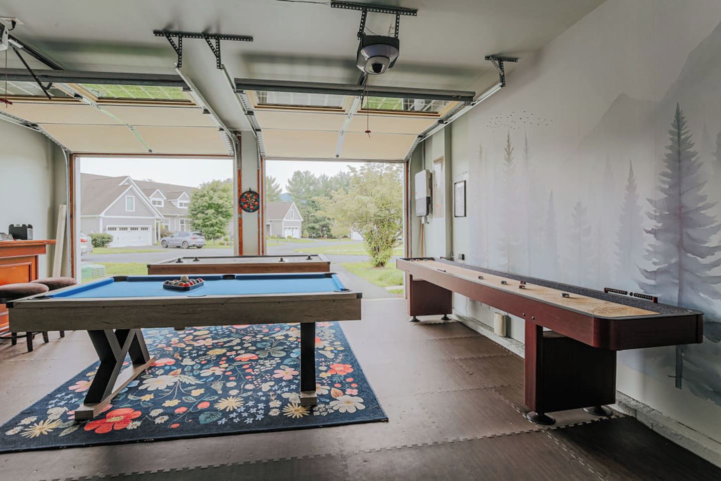 Area ricreativa interna con tavolo da biliardo, tavolo da calcio e vista su un quartiere residenziale.