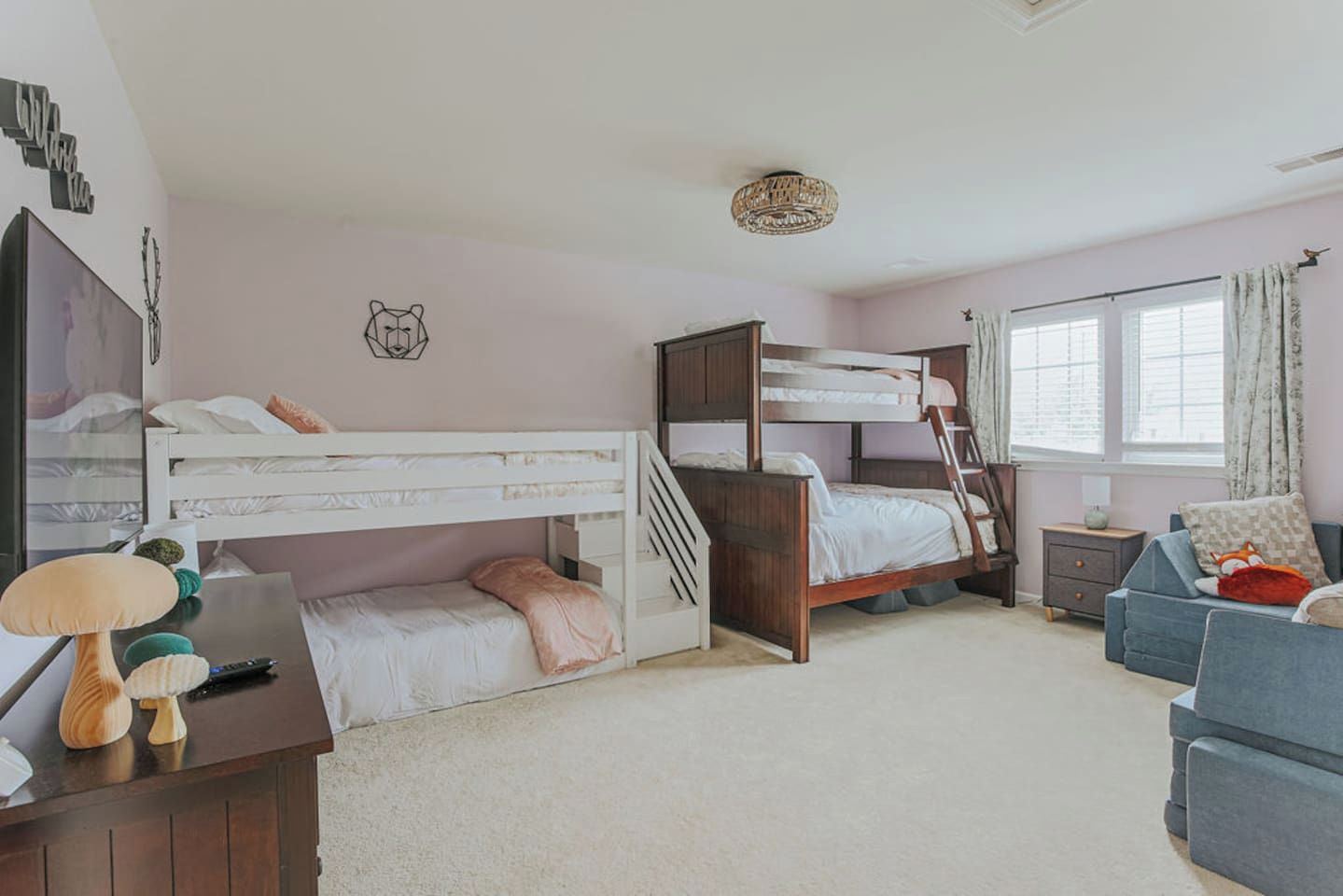 A bedroom with bunk beds, a desk, a chair, a lamp, a window with curtains, and a wall decoration.