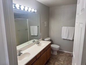 A bathroom with a double sink, a toilet, and a mirror with lights above. - Cozy 2-bedroom condo in marvelous Fountain Hills, Arizona (Fountain Hills)