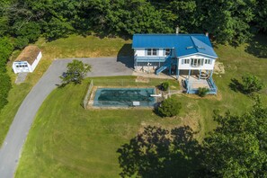 Et stort hus med blå tag, swimmingpool og en indhegnet have.