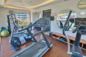 Ein Fitnessstudio mit Laufbändern, Gymbällen und einem Spiegel.