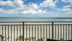 A balcony with a view of the beach and ocean.