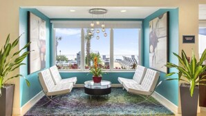 A modern lounge area with two white sofas, a round coffee table, and a view of the city through large windows.