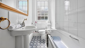 Ein Badezimmer mit weißem Waschbecken, Spiegel, Toilette und Badewanne.