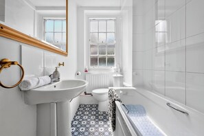 A bathroom with a white sink, a mirror, a toilet, and a bathtub. - Cozy Apartment Near Hyde Park  (London)
