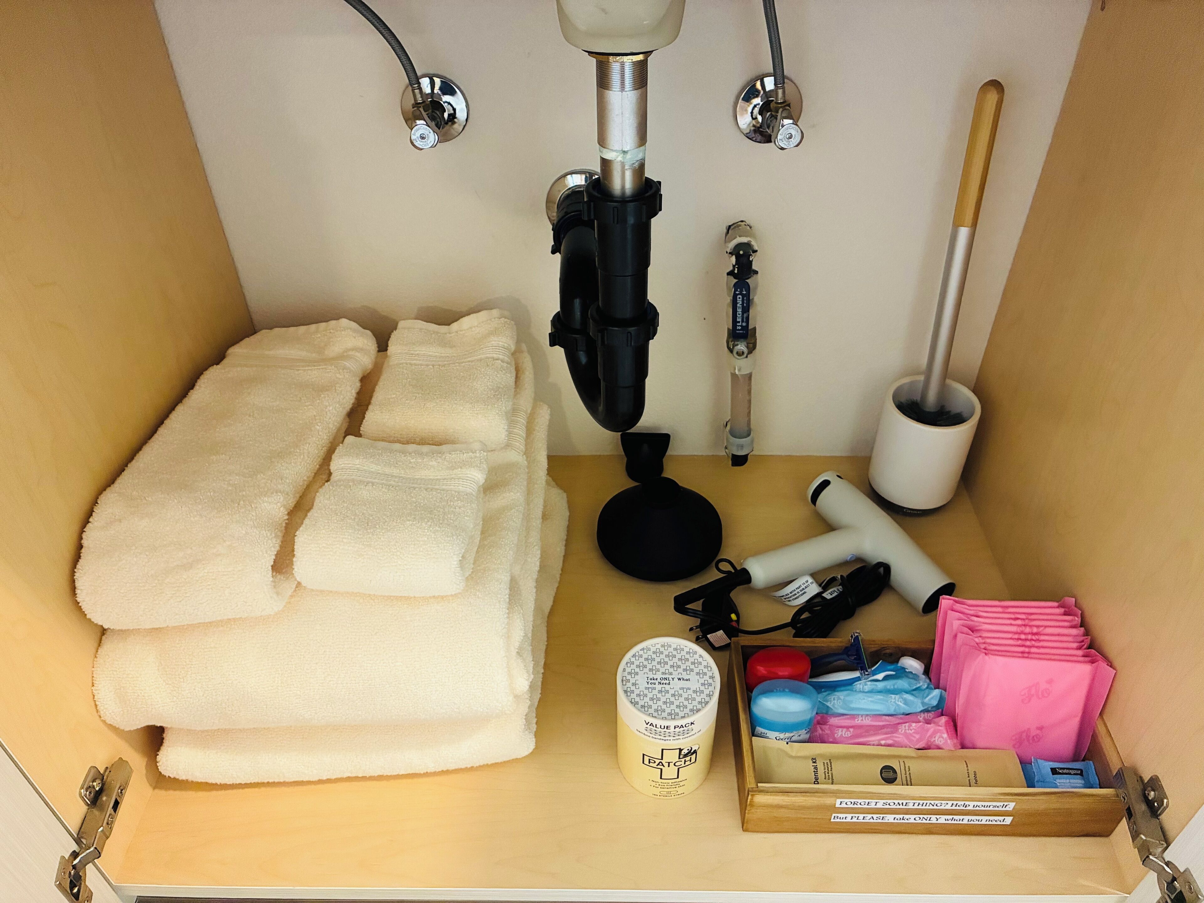 Um banheiro bem organizado com toalhas, chuveiro, mangueira de chuveiro, um frasco e uma caixa de produtos de higiene pessoal.
