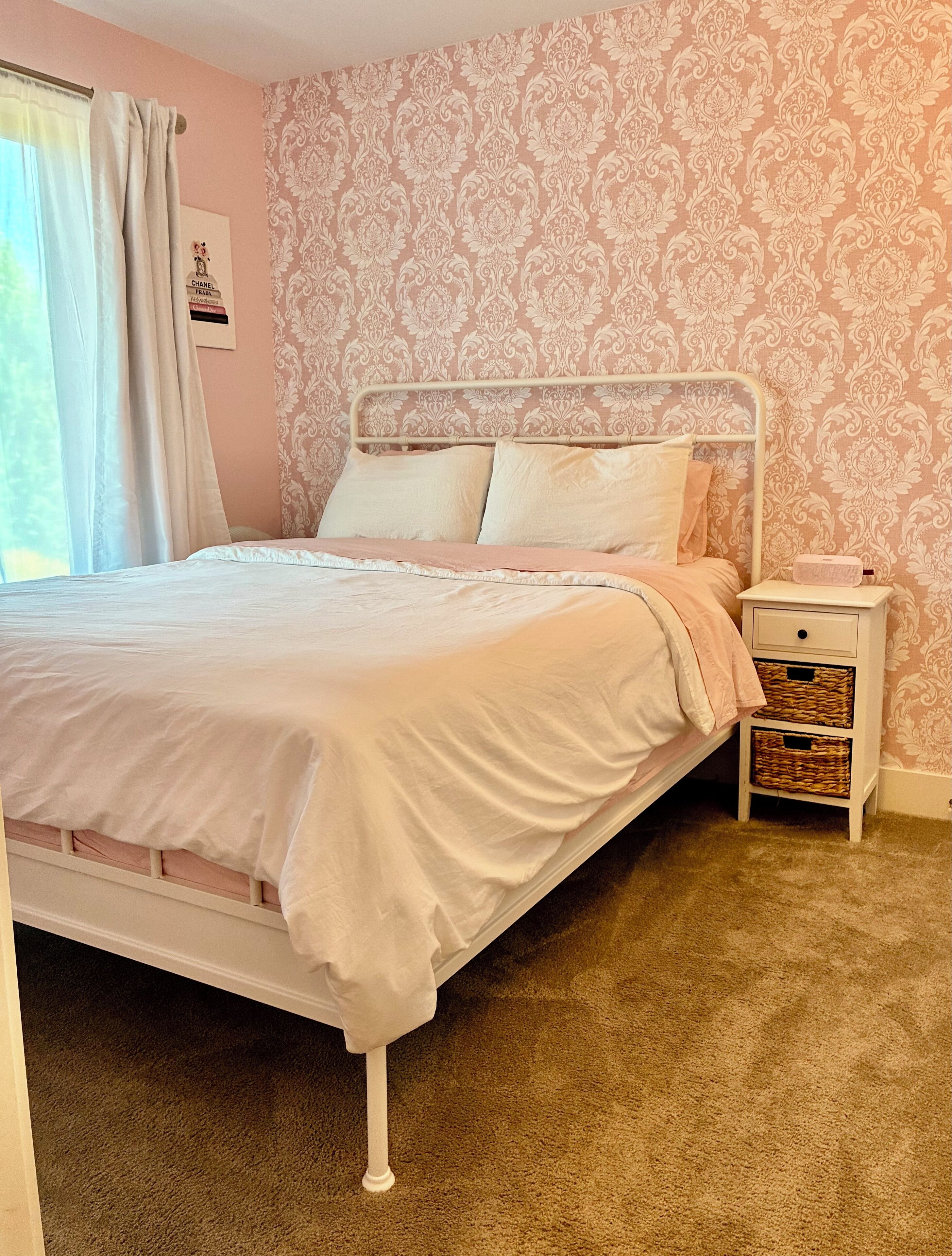 A bedroom with a bed, a nightstand, and a wall with a patterned wallpaper.
