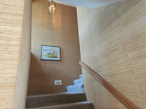 Una escalera con barandilla de madera y un cuadro en la pared.