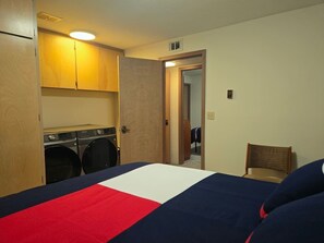 Een hotelkamer met een bed, een stoel, een wasmachine en een spiegel.