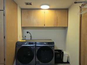A laundry room with two front-loading washing machines and a dryer. - Tranquil Bluff retreat W/ Water Views & Game Room (Marrowstone)