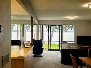 A room with a large window, a desk, a chair, a television, and a view of a body of water. - Tranquil Bluff retreat W/ Water Views & Game Room (Marrowstone)