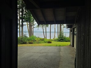 A covered parking area with a view of a lake and trees. - Tranquil Bluff retreat W/ Water Views & Game Room (Marrowstone)