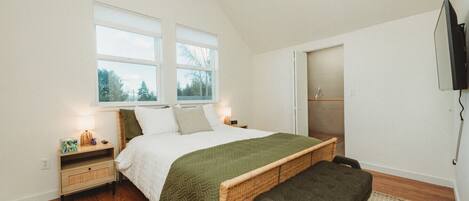A bedroom with a bed, bedside tables, a bench, a television, and a window.