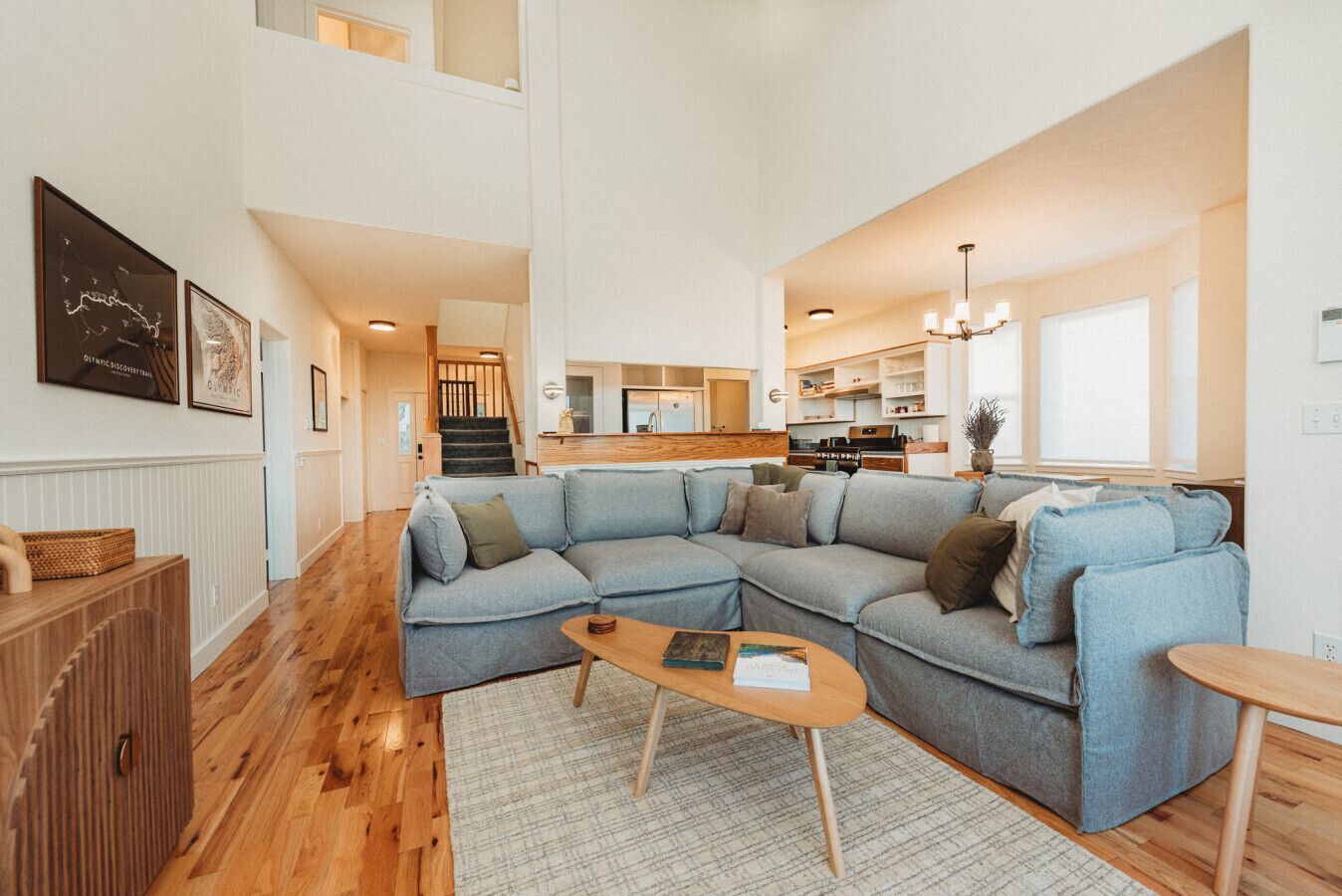 A spacious living area with a large sectional sofa, a wooden coffee table, and a staircase leading to an upper floor.