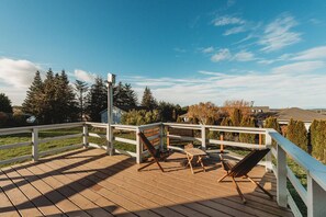 A wooden deck with a white railing, two lounge chairs, and a clear view of the surrounding landscape. - Farm Cottage in Sequim w/ Fenced Orchard (Sequim)