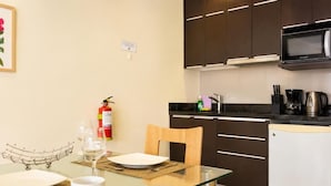 A modern kitchen with dark cabinets, a microwave, and a coffee maker. - Diez Canseco 2W Apartments Service (Miraflores)