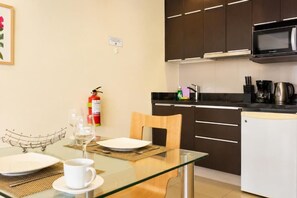 A modern kitchen with dark cabinets, a microwave, and a coffee maker. - Diez Canseco 2W Apartments Service (Miraflores)