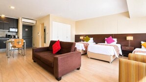 A hotel room with a sofa, two beds, a dining area, and a kitchenette. - Diez Canseco 2W Apartments Service (Miraflores)