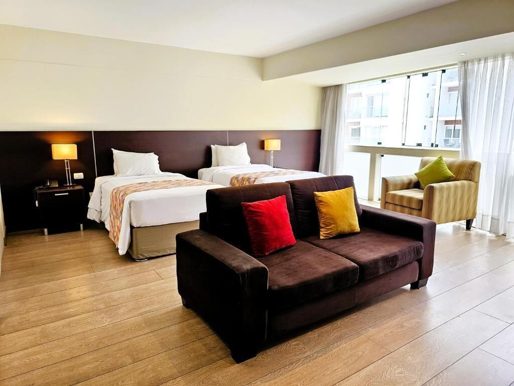 Habitación de hotel con dos camas, un sofá y una silla.