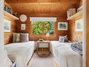 A cozy cabin room with two beds, a window with a view of greenery, and wooden walls. - "Greta" - 1.7km from the sea by Interhome (Rørvig)