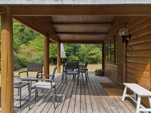 A covered outdoor deck with wooden flooring, metal chairs, a table, and a bench. - "Greta" - 1.7km from the sea by Interhome (Rørvig)